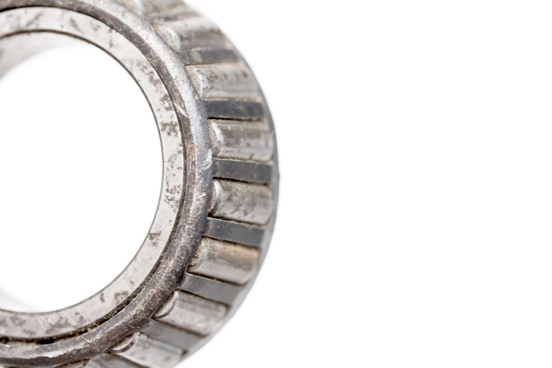 close up of rusted needle roller bearing on a white background