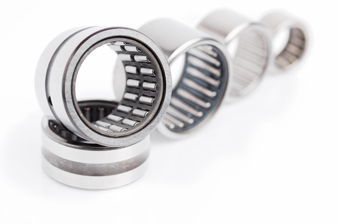 a row of needle roller bearings, in various sizes, isolated on a white background
